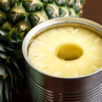 Pineapple Rings In Tin On Dark Wood Next To Pineapple.